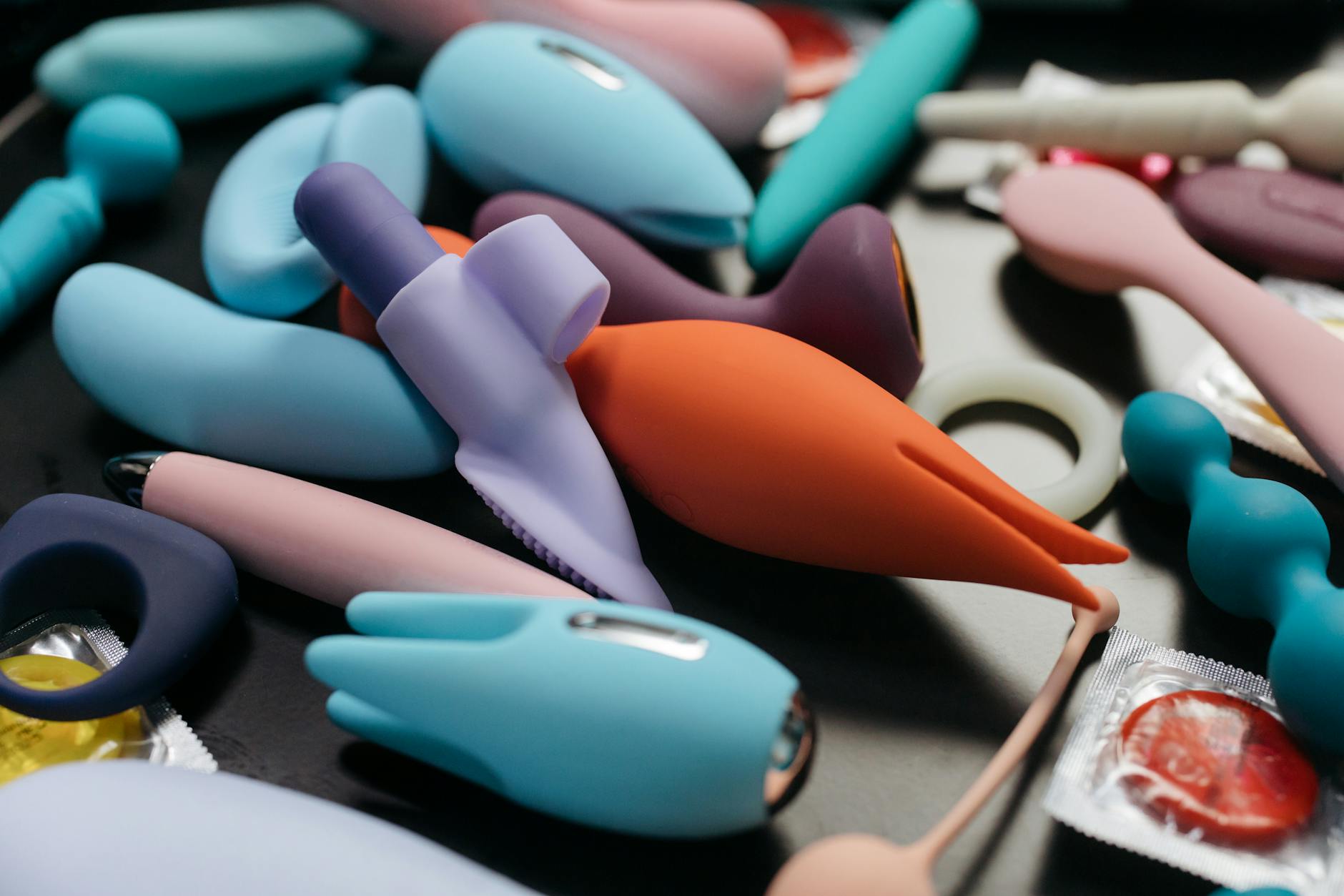 Colorful vibrators with flowers in a holographic gift bag against a bold yellow background