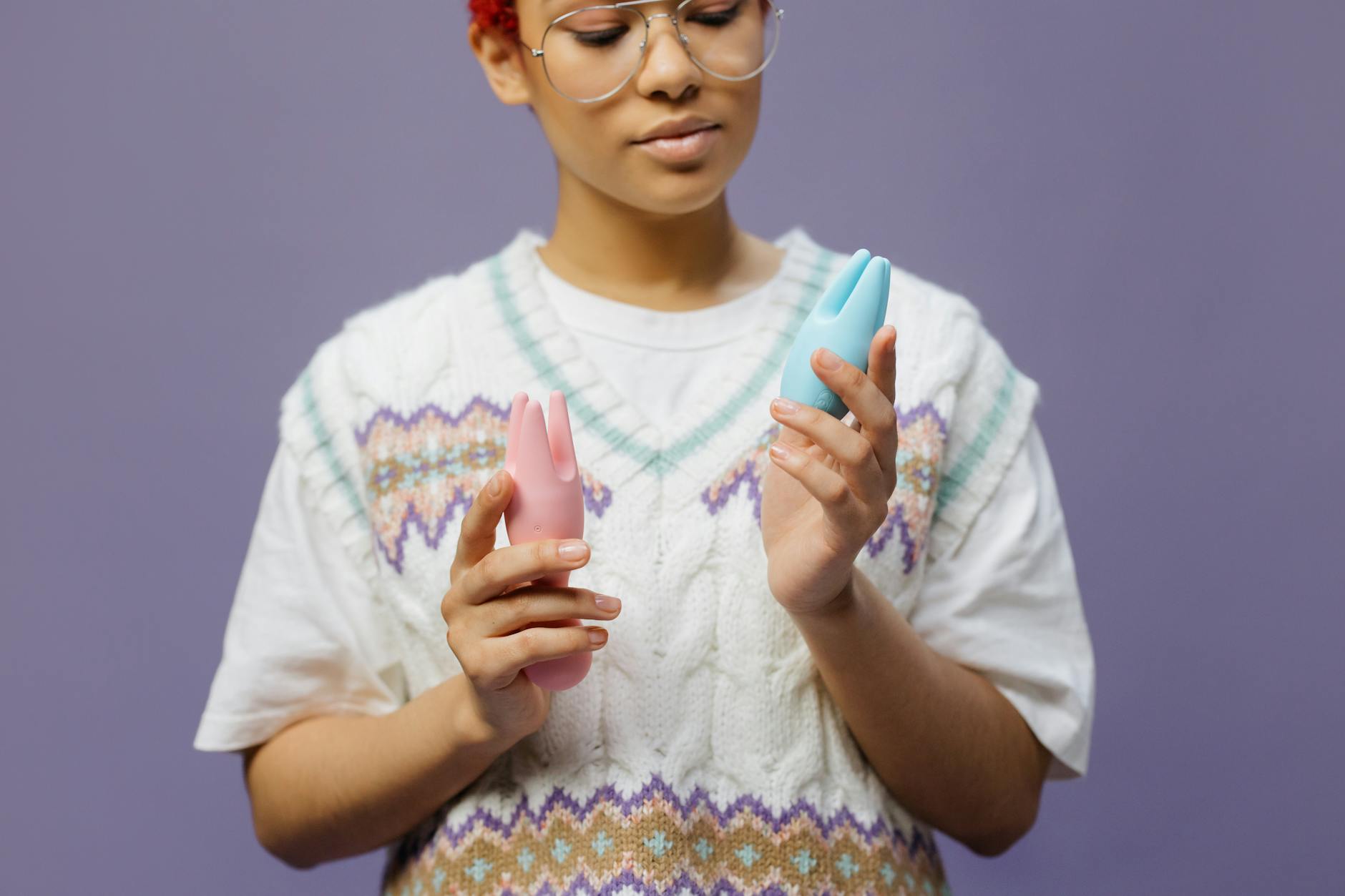 Woman holding and examining silicone clitoral vibrators in different colors