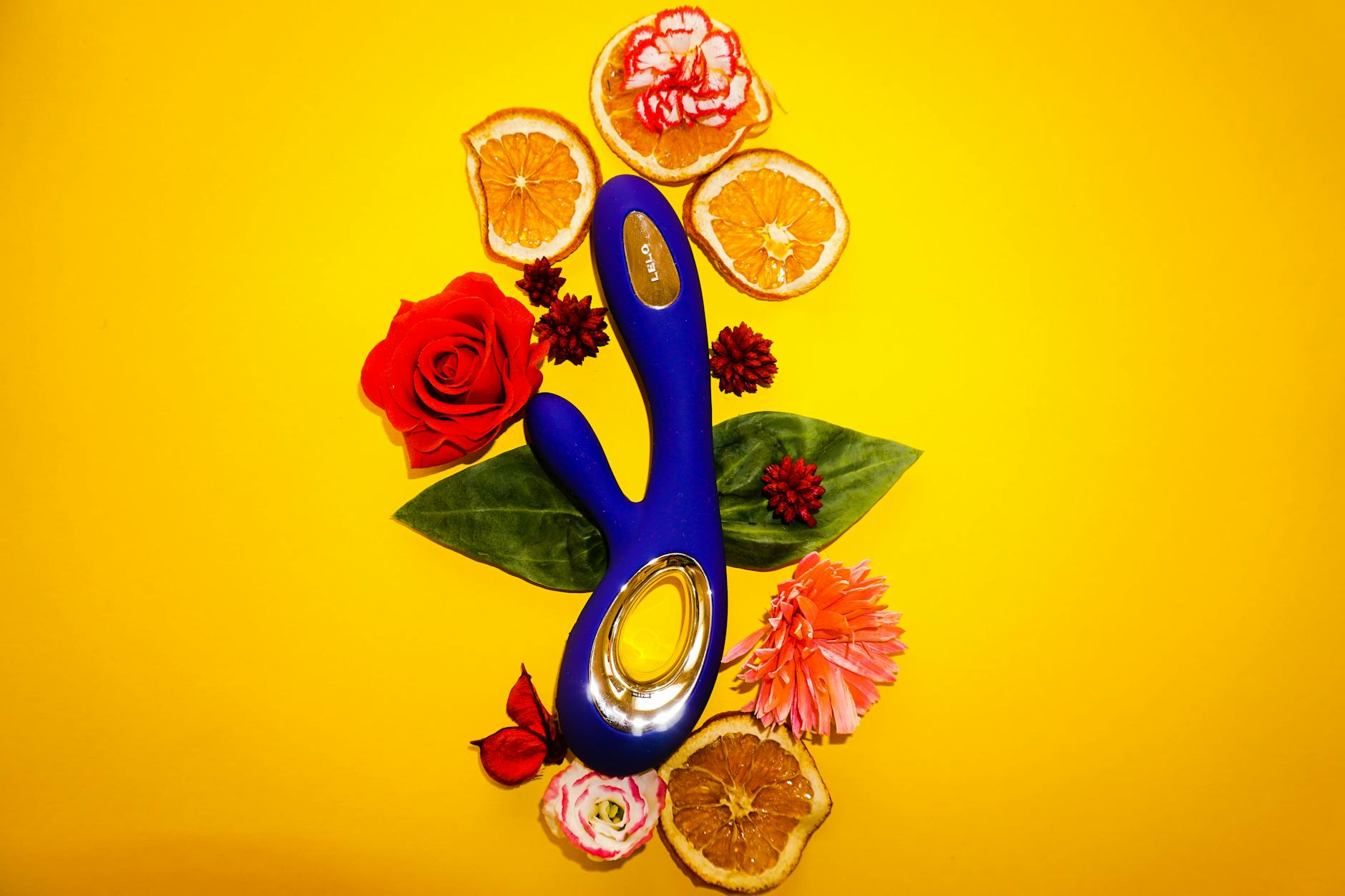 A silicone lemon vibrator held in hand against a solid purple background, demonstrating gentle intimate product design.