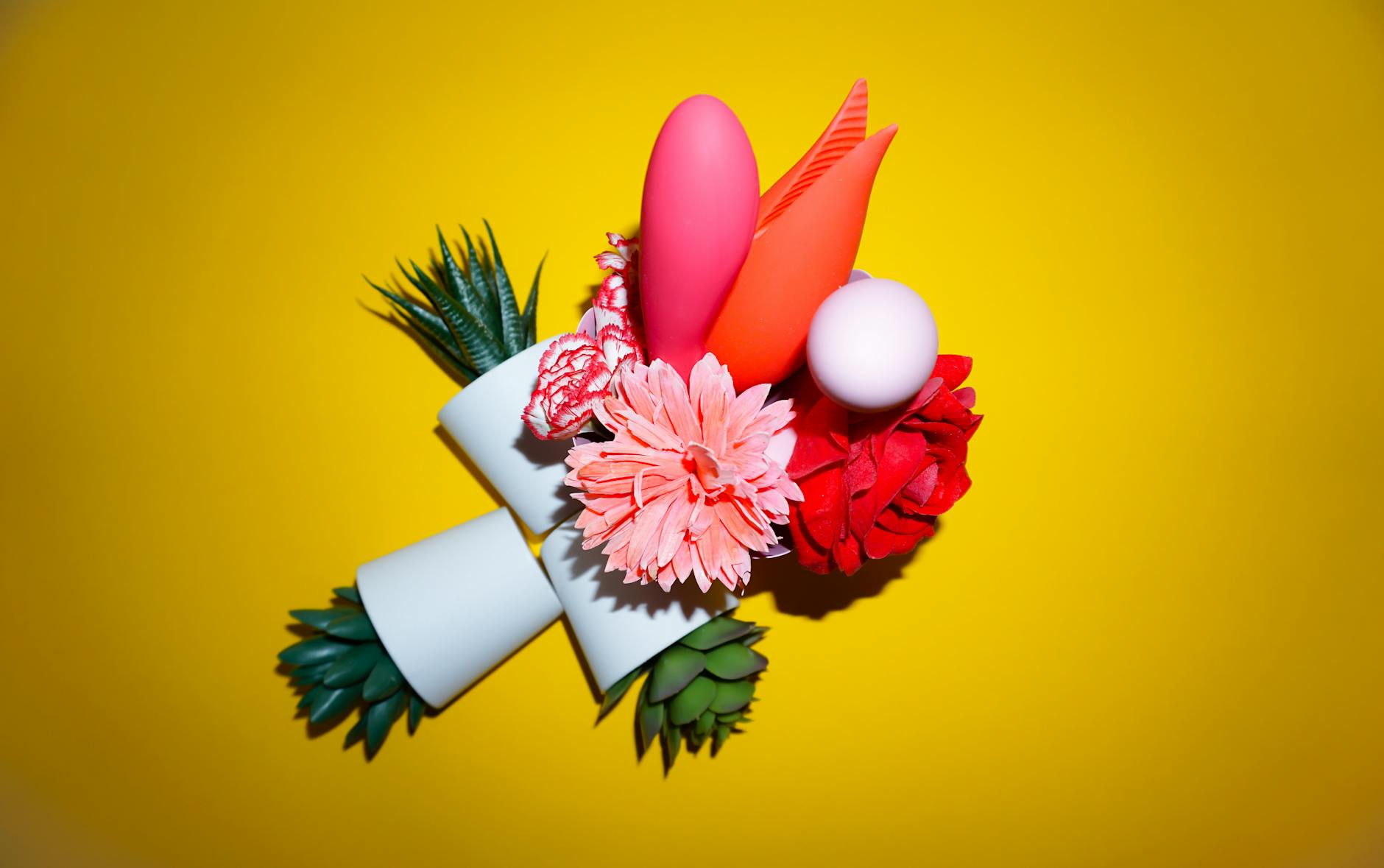 A hand reaching over a variety of colorful lemon vibrators and clitoral toys arranged on a table